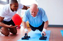 Trainer helping senior citizen do push-ups (iStockphoto)