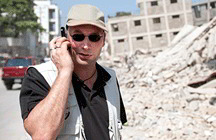 Man on phone in front of building destroyed by quake (iStockphoto)
