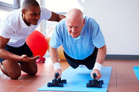 Trainer helping senior citizen do push-ups (iStockphoto)
